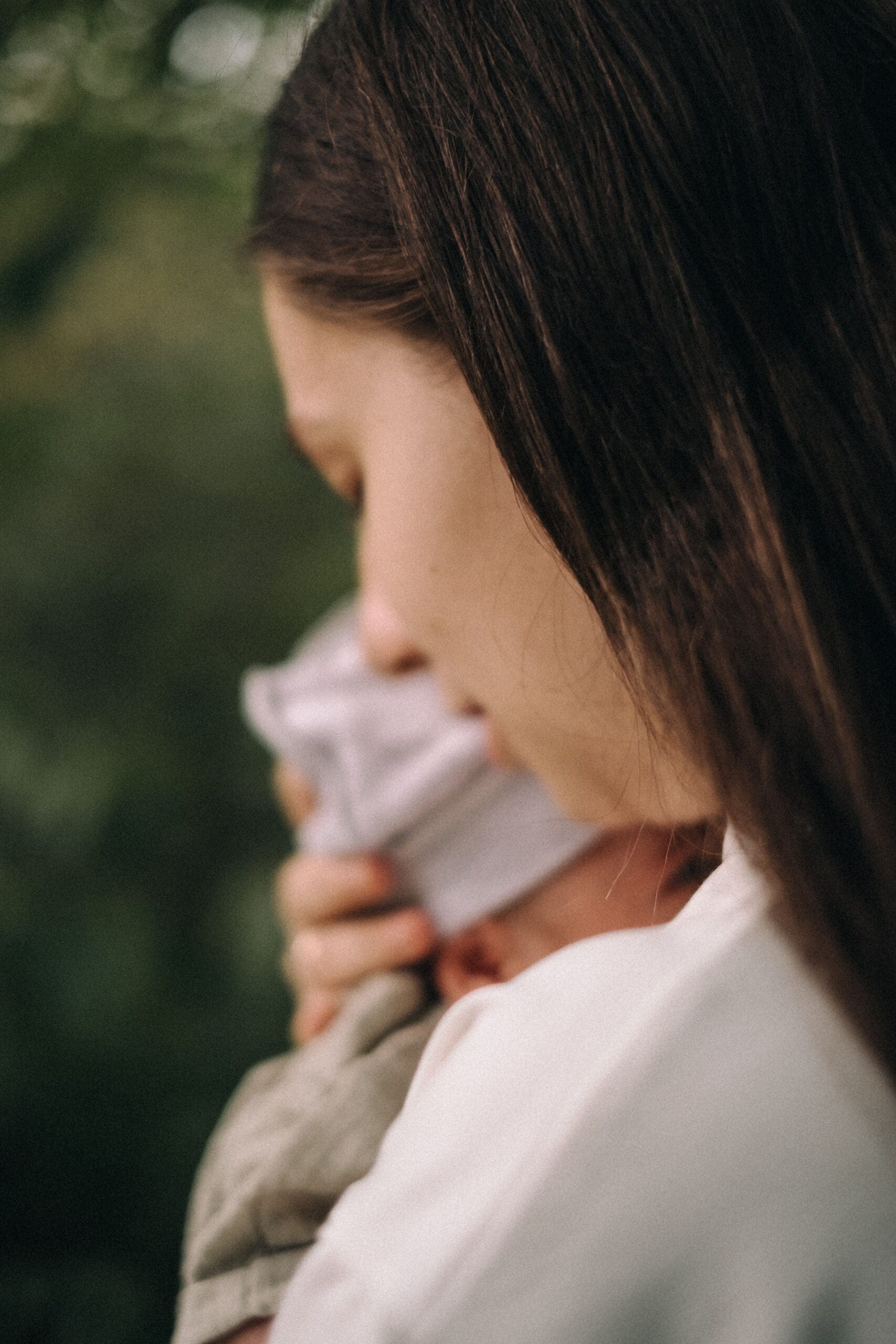 Woman holding a baby while looking down thoughtfully