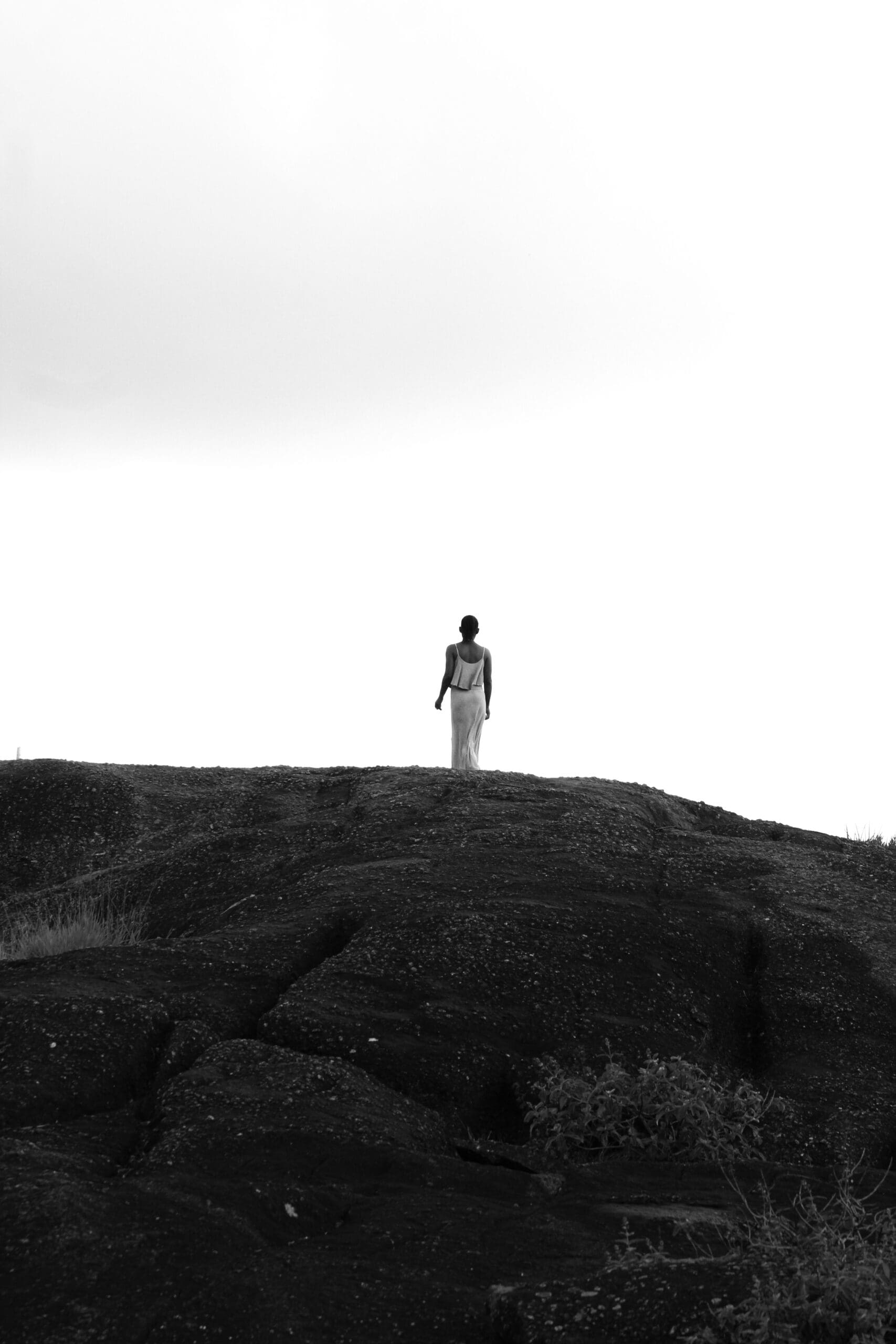 Woman walking alone across a large rocky landscape